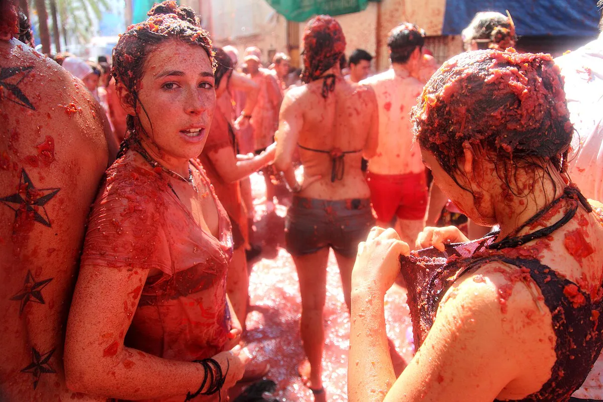 Crowds drenched in tomato pulp in a narrow Bunol street during La Tomatina — 1